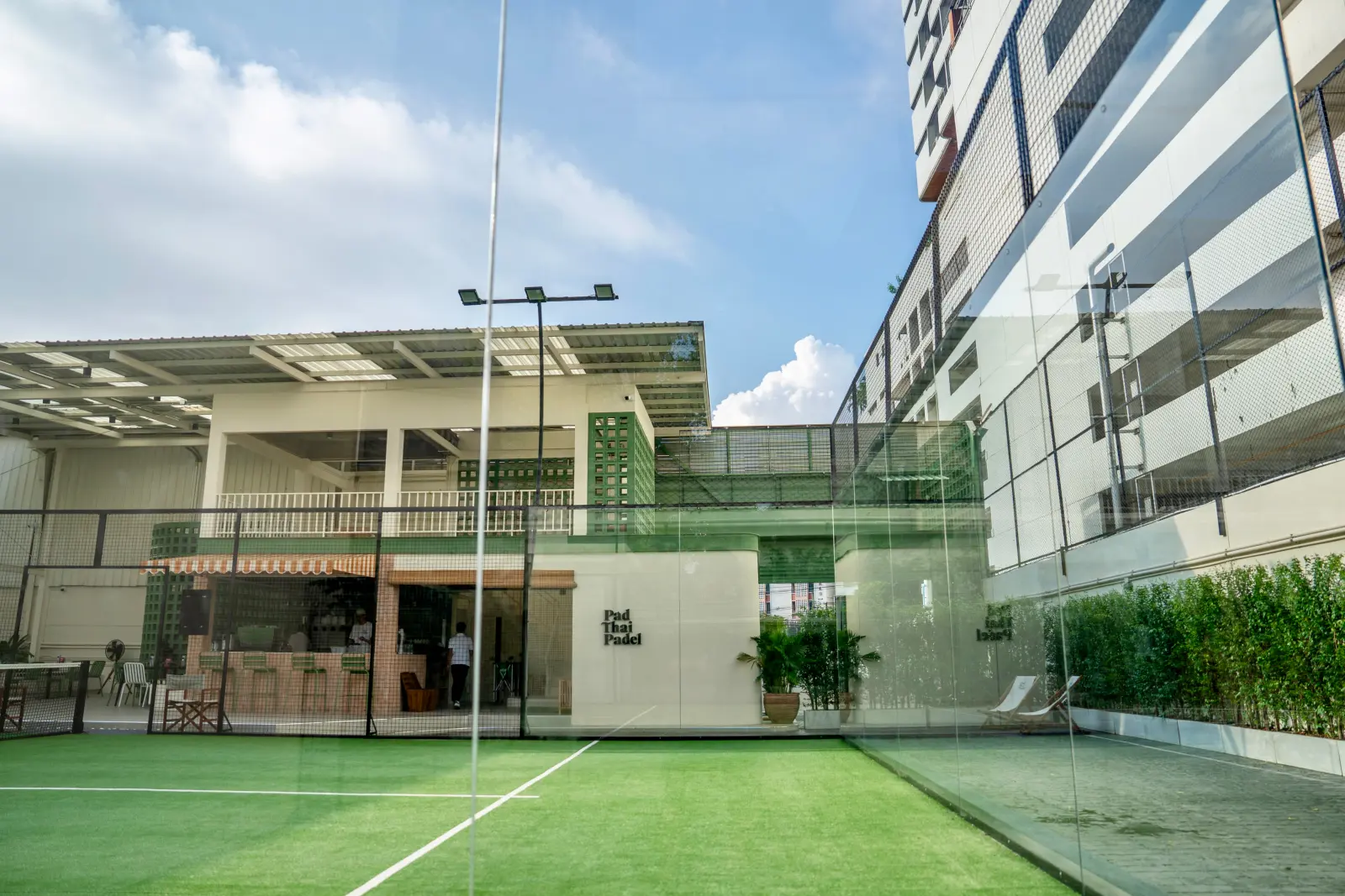Glass padel court at Pad Thai Padel Rama 4 with a Bangkok tower rising behind it